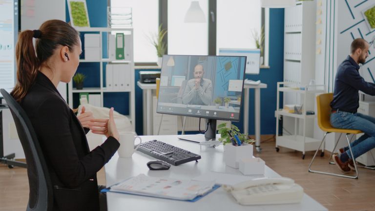 Profesional trabajando desde una oficina virtual bien organizada con ordenador, herramientas digitales y espacio de coworking al fondo